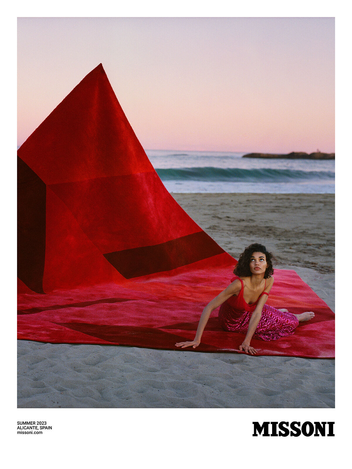 A model wears a red dress from the Summer 2023 collection