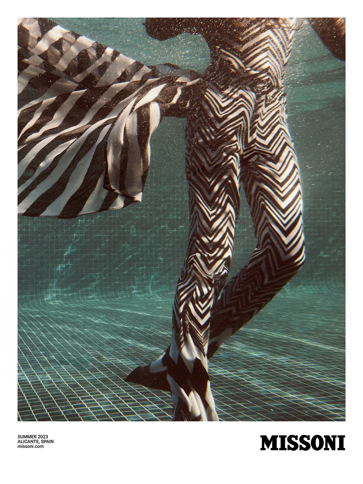 A model, who is inside a swimming pool, is wearing a jumpsuit from the Summer 2023 Collection A model, who is inside a swimming pool, is wearing a jumpsuit from the Summer 2023 Collection